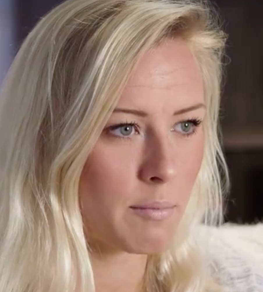 Blonde Frau mit blauen Augen im Vordergrund, unscharfer Hintergrund, die besorgt wirkt.