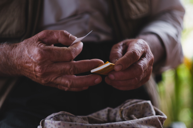 Alter Mann hält ein Blatt Papier und sieht besorgt aus, mit unscharfem Hintergrund, wahrscheinlich aufgrund von Demenz.