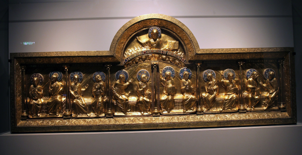 Prunkvoller goldener Museumsrahmen mit detaillierten Skulpturen, vor einer neutralen Wand.