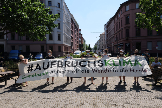 Menschen mit Masken halten ein Banner mit der Aufschrift 'Aufbruchsklima' während einer Klimaprotest in Berlin, Deutschland.