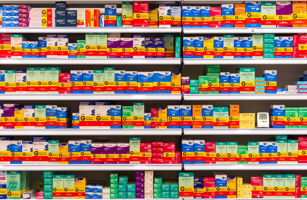 Ein Regal in einer Apotheke, das mit verschiedenen Medikamenten befüllt ist, darunter Schachteln, die ordentlich auf den Regalen angeordnet sind.