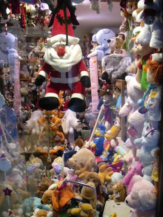 Eine Weihnachtsopa doll steht im Mittelpunkt, umgeben von Teddybären und anderen Puppen auf der rechten Seite.