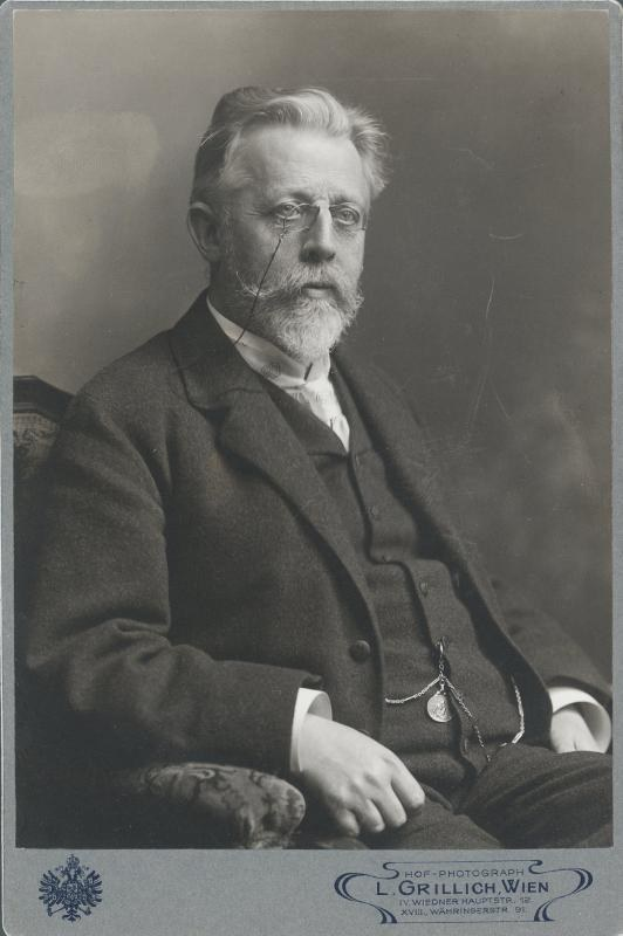 Schwarz-weiß-Porträt eines bärtigen Mannes mit Brille, der in einem Stuhl sitzt, beschriftet mit "L. Grillich Wien, der Gründer der deutschen Revolution."