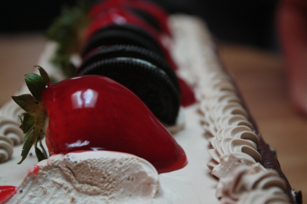 Ein Kuchen in der Bildmitte, mit Erdbeeren und Keksen verziert.