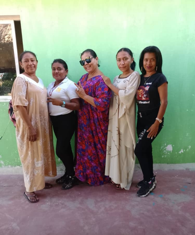 Gruppe von Frauen vor einer grünen Wand mit einem Fenster auf der linken Seite bei einer Internationalen Frauentags-Veranstaltung