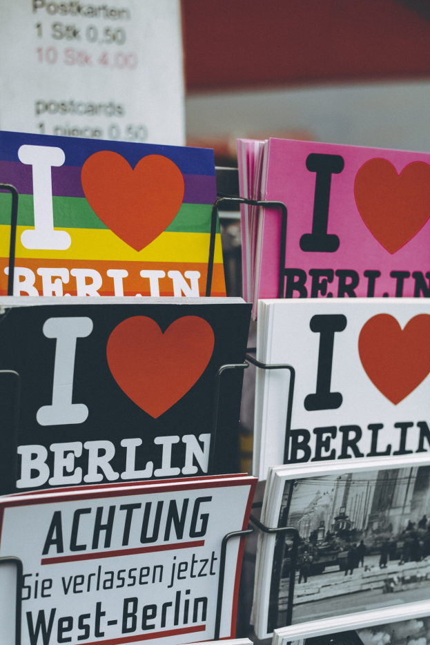 Ein Gestell mit Büchern und Postern, die den Satz "Ich liebe Berlin" zeigen, vor einem leicht unscharfen, träumerischen Hintergrund.
