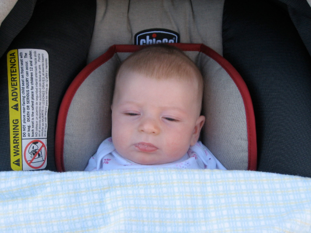 Ein Baby liegt unter einem Babybett mit einem Warnaufkleber auf der linken Seite.