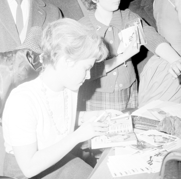 Schwarz-weiß-Foto von Prinzessin Diana, die an einem Tisch ein Buch liest, umgeben von Papieren und anderen Gegenst├Ąnden.