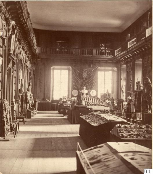 Schwarz-weiß-Fotografie eines Raums im Museum of Fine Arts, London, gefüllt mit Tischen, Stühlen, Skulpturen an den Wänden, Fenstern, Vorhängen und Geländern.