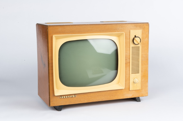 Ein altmodischer Fernseher mit einem hölzernen Rahmen und einem schwarzen Bildschirm steht auf einer weißen Oberfläche vor einem hellen weißen Hintergrund.