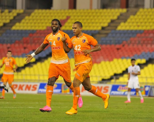 Eine Gruppe von Männern, die auf einem Rasenfußball spielen, tragen die Farben der Indian Super League 2019-20, mit Werbetafeln, Stühlen, Säulen und Wänden im Hintergrund.