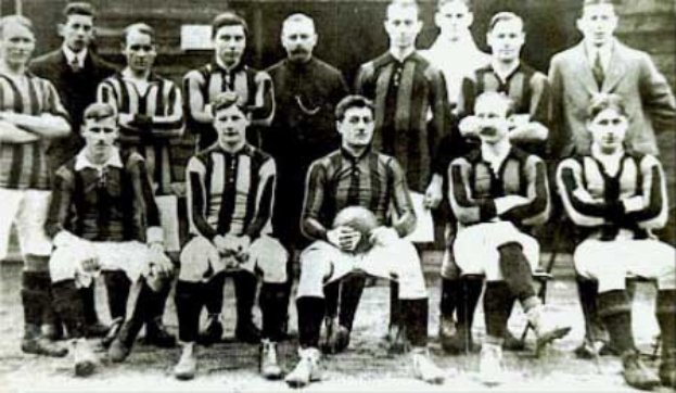 Ein Schwarz-Weiß-Foto einer Füßballmannschaft, einige stehen, einige sitzen, vor einer Wand, mit dem Text "Ballymena Football Club" unten.