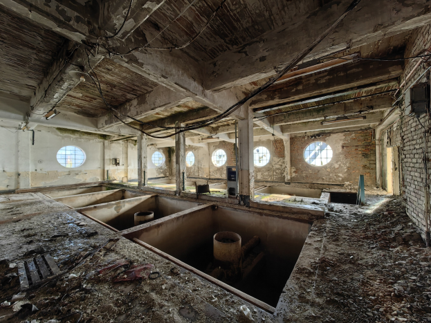 Verlassenes Gebäude-Innere im Chernobyl-Ausschlussgebiet, das verstreute Trümmer, freiliegende Wände, Decke und bauliche Elemente wie Fenster und Säulen zeigt.