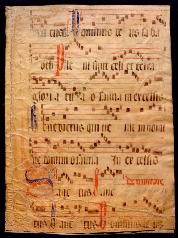 Ein illuminiertes Manuskript mit Musiknotation auf einem Blatt Papier vor einem dunklen Hintergrund, gefüllt mit Text und musikalischen Symbolen, die ein komplexes Design ergeben.