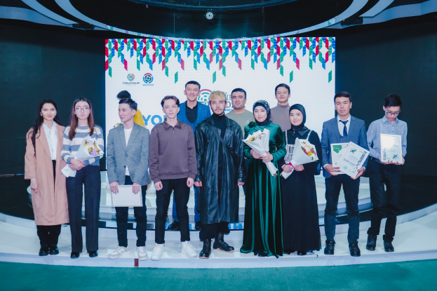 Eine Gruppe von Menschen auf einer Bühne, jeder hält einen Blumenstrauß und Urkunden in den Händen, im Hintergrund ein Schild mit der Aufschrift "Youth Solar Awards 2019".