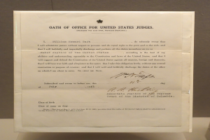 Ein Blatt mit dem Text "Eid für Bundesrichter" liegt auf einem Tisch vor einer Wand.