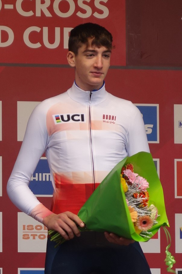 Ein Mann steht auf einem Podium und hält einen Blumenstrauß, feiert einen Sieg mit selbstbewusster und stolzer Haltung.