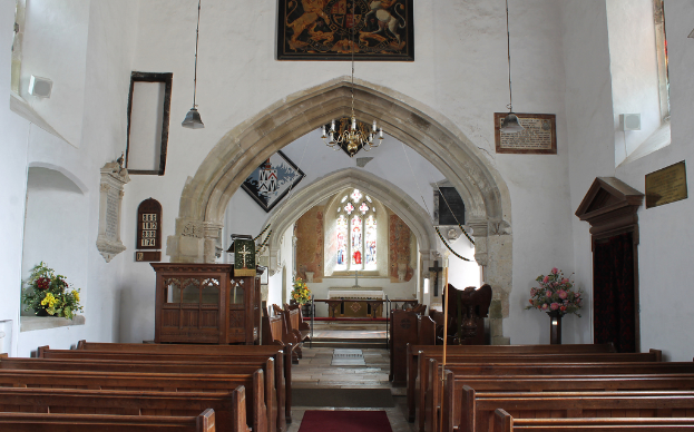 Ein Innenblick in eine Kirche mit Blumenvasen, Fotoeinrahmungen und Lichtern in der Mitte und Bänken unten.