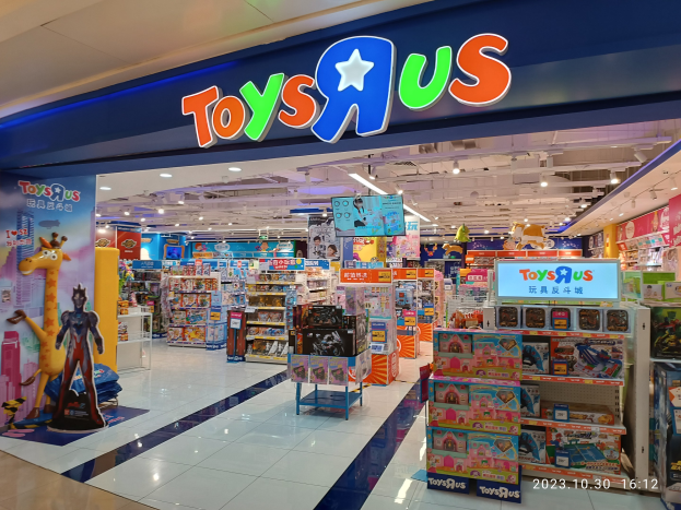 Ein Toys R Us-Laden in einem Einkaufszentrum mit Regalen voller Spielzeug, einem Namensschild, Deckenleuchten und einem Wasserzeichen in der rechten unteren Ecke.