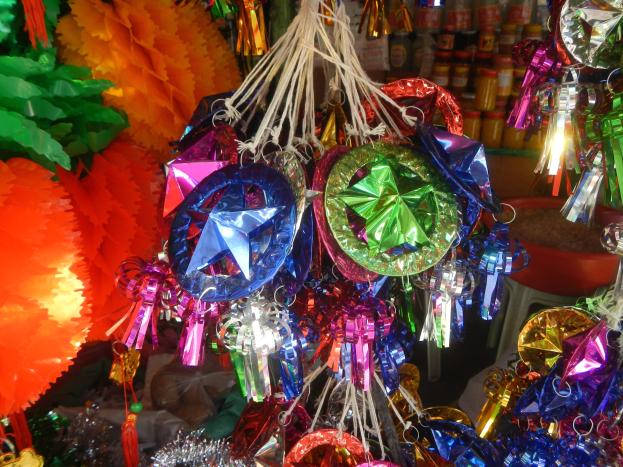 Farbenfrohe Dekorationen wie Laternen und Bänder hängen von der Decke über Regalen voller Flaschen in einer festlichen Atmosphäre.