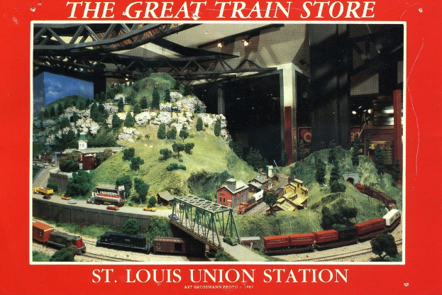 Ein Plakat mit einer Eisenbahn"ubung "uber eine Br"ucke mit einer Tr"agerkonstruktion, umgeben von Pflanzen, H"usern und H"geln.