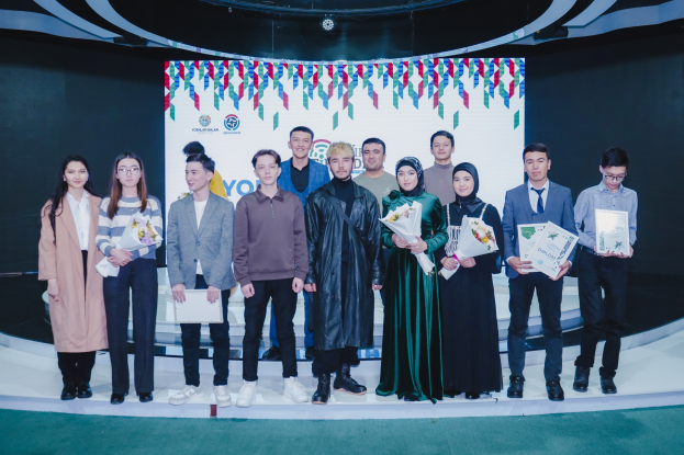 Eine Gruppe von Menschen auf einer Bühne mit Blumensträußen und Urkunden, im Hintergrund ein "Jugend-Solar-Awards 2019"-Plakat