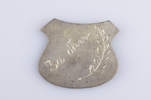 Ein silbergerändertes Abzeichen mit einem Lorbeerkranz, darauf die Inschrift "50. Geburtstag", vor einem weißen Hintergrund.