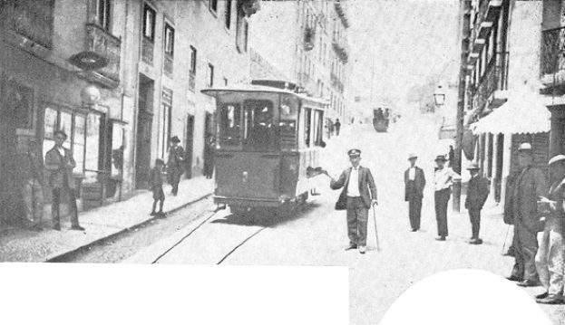 Ein Schwarz-Weiß-Foto einer Stadtstraße mit einer Tram, Fußgängern auf dem Gehweg, Gebäuden mit Fenstern auf beiden Seiten und anderen Fahrzeugen im Hintergrund.