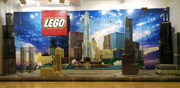 Bunte Lego-Kreationen auf einem Boden mit einer Wand im Hintergrund.