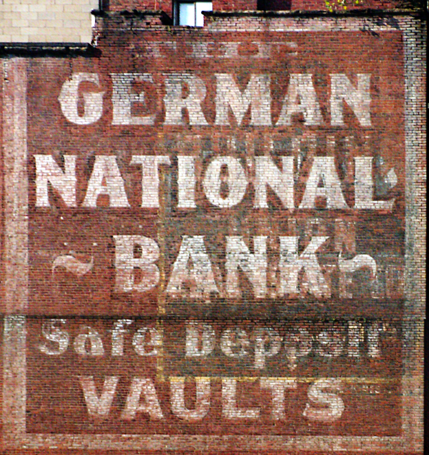 Eine Ziegelwand mit einem Schild, auf dem "Deutsche Nationalbank-Schließfächer" steht, und einem Fenster oben drauf.