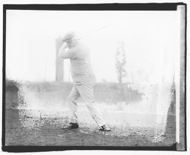 Schwarz-weiß-Foto eines Mannes, der einen Golfschläger auf einem Rasen mit Bäumen und Pflanzen im Hintergrund schwingt.