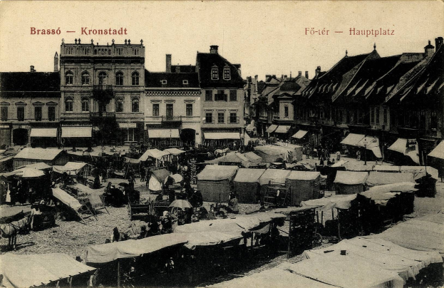 Schwarz-weiß-Foto eines belebten Marktes in Kronstadt, Deutschland, mit Menschen, Zelten und Gebäuden im Hintergrund.