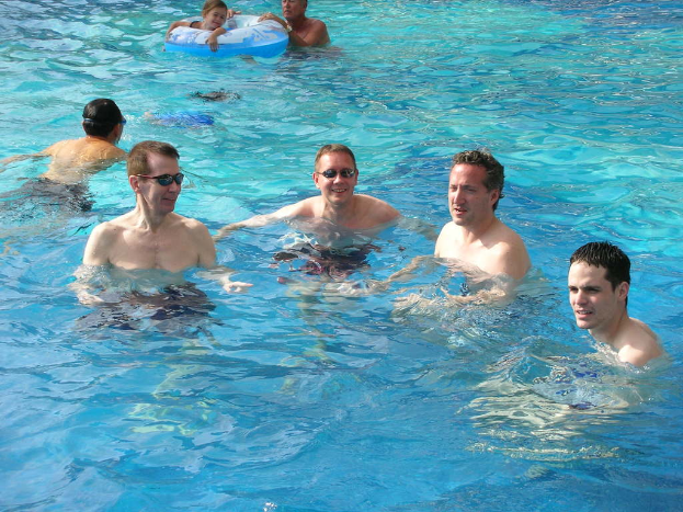 Mehrere Männer schwimmen im Wasser, während ein Mädchen mit einem Ballon schwimmt, den jemand hält.