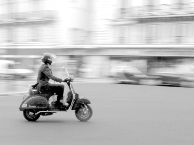 Eine Person fährt einen Roller auf einer Straße.