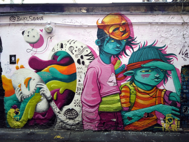 Mit Graffiti bedecktes Gebäude mit einer Straße unten, Strommasten und einem klaren blauen Himmel im Hintergrund.