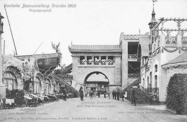 Schwarz-weiß-Foto von Menschen, die eine Straße in Dresden, Deutschland im Jahr 1900 entlanggehen, mit Gebäuden, Pflanzen und Stühlen, die die Straße säumen und dem Himmel im Hintergrund.