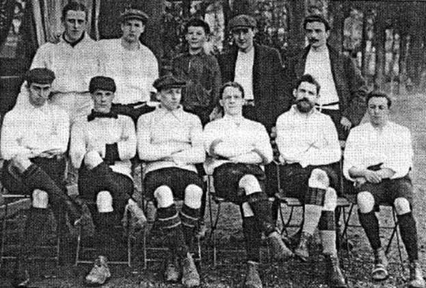 Schwarzes und weißes Mannschaftsfoto des West Bromwich Albion Football Club aus dem Jahr 1918, das Männer sitzend und stehend mit Bäumen im Hintergrund zeigt.